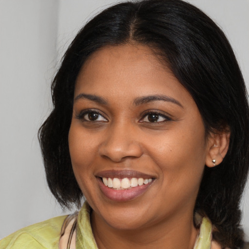 Joyful black young-adult female with long  brown hair and brown eyes