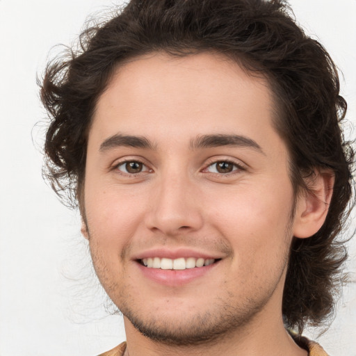 Joyful white young-adult male with long  brown hair and brown eyes