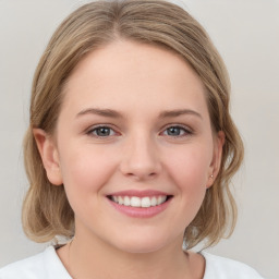 Joyful white young-adult female with medium  brown hair and grey eyes