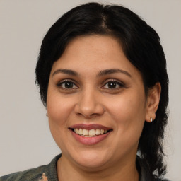 Joyful latino adult female with medium  brown hair and brown eyes