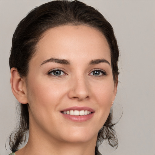 Joyful white young-adult female with medium  brown hair and grey eyes