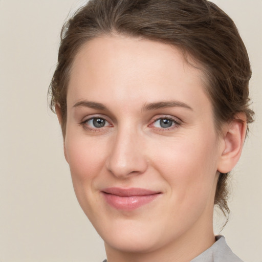 Joyful white young-adult female with medium  brown hair and grey eyes