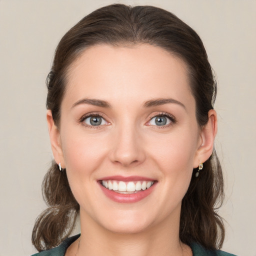 Joyful white young-adult female with medium  brown hair and grey eyes