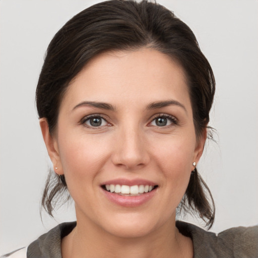 Joyful white young-adult female with medium  brown hair and grey eyes