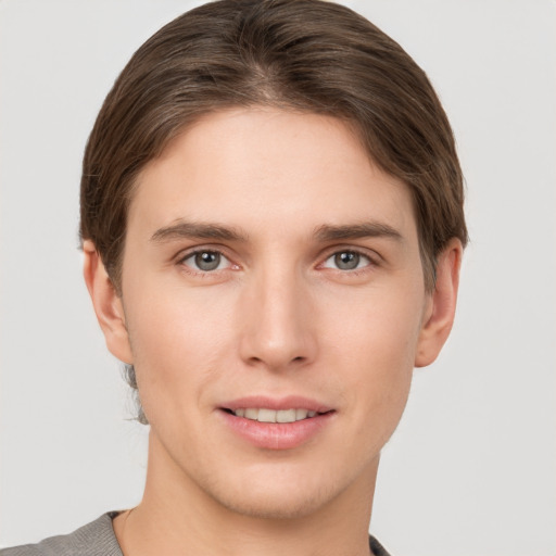 Joyful white young-adult male with short  brown hair and grey eyes