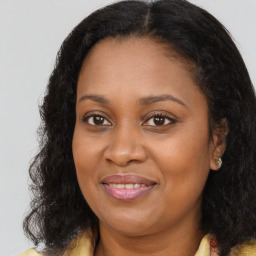 Joyful black adult female with long  brown hair and brown eyes