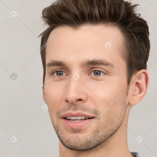 Joyful white young-adult male with short  brown hair and grey eyes