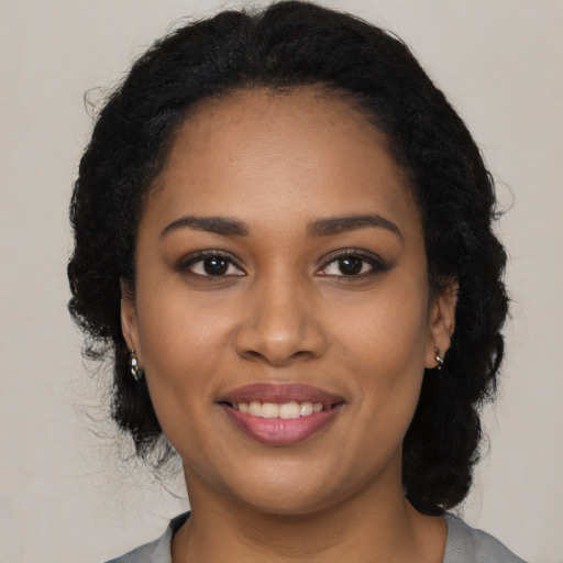 Joyful black young-adult female with long  black hair and brown eyes