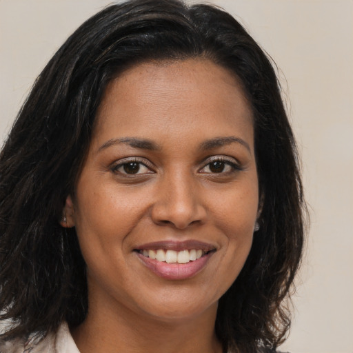 Joyful black young-adult female with long  brown hair and brown eyes