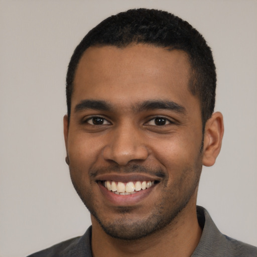 Joyful black young-adult male with short  black hair and brown eyes