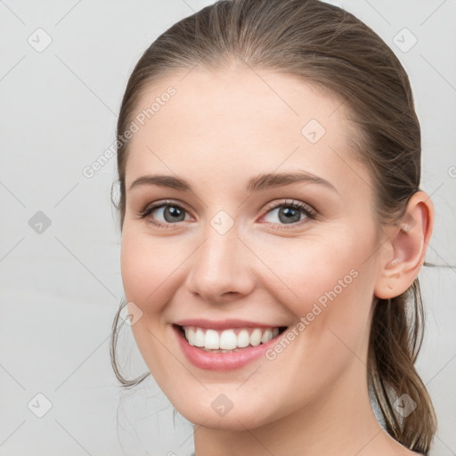 Joyful white young-adult female with medium  brown hair and grey eyes