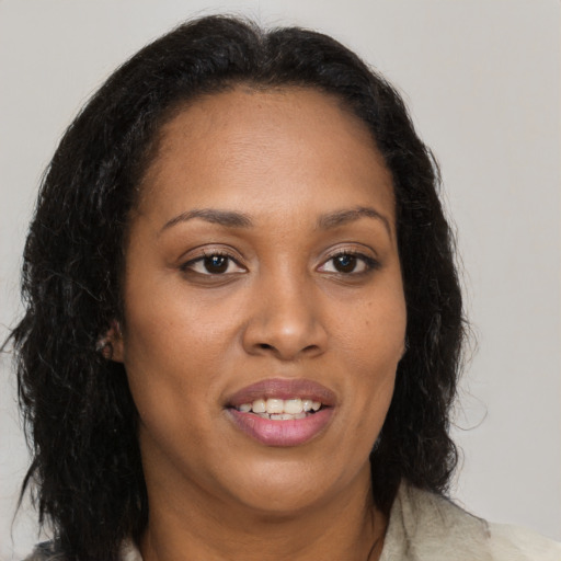 Joyful black young-adult female with long  brown hair and brown eyes