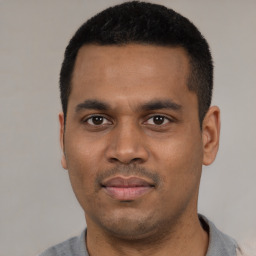 Joyful latino young-adult male with short  black hair and brown eyes