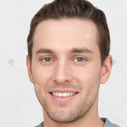 Joyful white young-adult male with short  brown hair and grey eyes