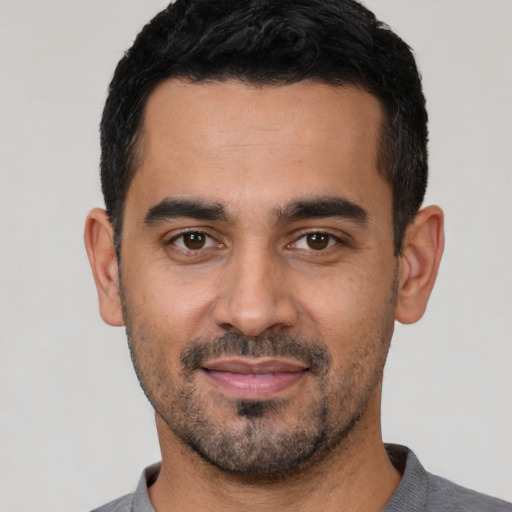 Joyful latino young-adult male with short  black hair and brown eyes