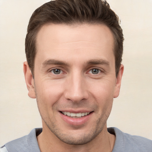 Joyful white young-adult male with short  brown hair and grey eyes