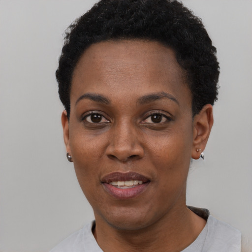 Joyful black young-adult female with short  black hair and brown eyes