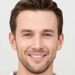 Joyful white young-adult male with short  brown hair and grey eyes