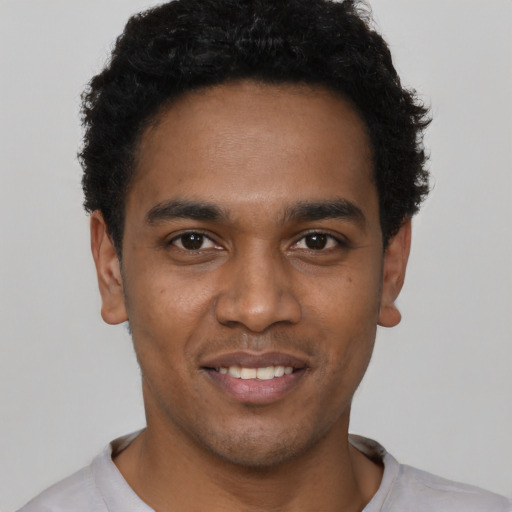 Joyful black young-adult male with short  black hair and brown eyes