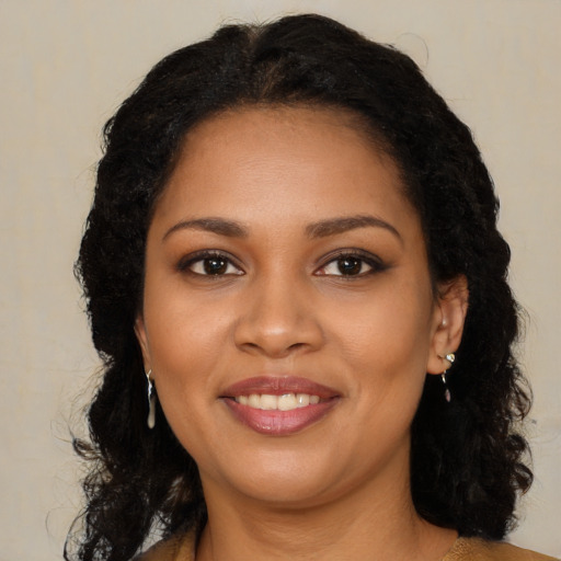 Joyful black young-adult female with long  brown hair and brown eyes
