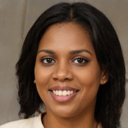 Joyful black young-adult female with long  brown hair and brown eyes