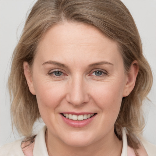 Joyful white adult female with medium  brown hair and grey eyes