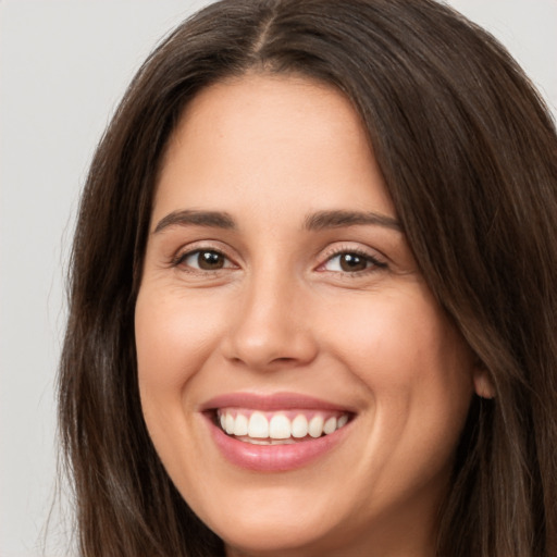 Joyful white young-adult female with long  brown hair and brown eyes