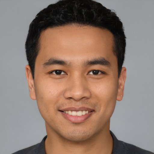 Joyful latino young-adult male with short  black hair and brown eyes