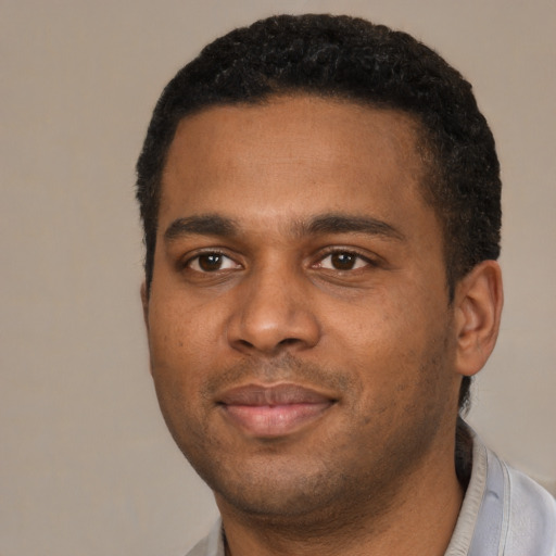 Joyful black young-adult male with short  black hair and brown eyes