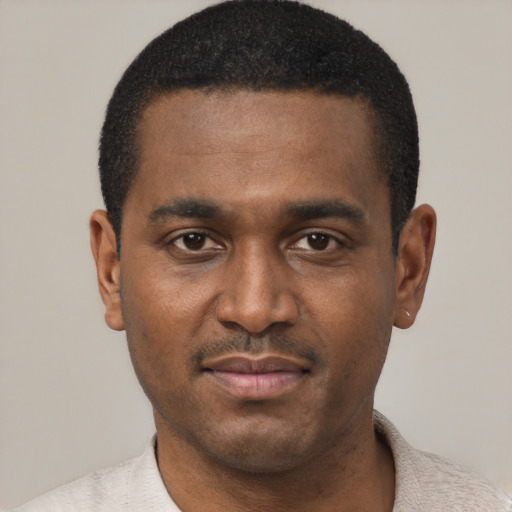 Joyful black young-adult male with short  black hair and brown eyes
