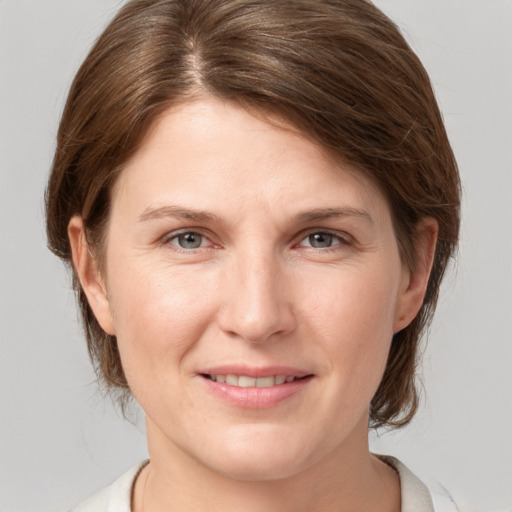 Joyful white young-adult female with medium  brown hair and grey eyes