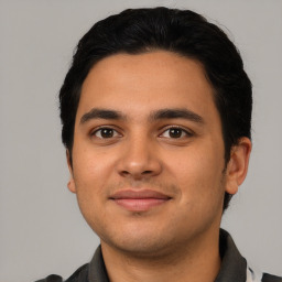 Joyful latino young-adult male with short  black hair and brown eyes