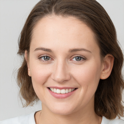 Joyful white young-adult female with medium  brown hair and grey eyes