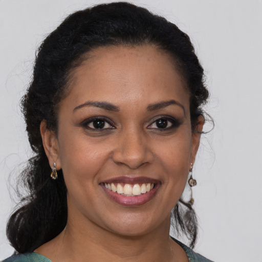 Joyful black young-adult female with long  brown hair and brown eyes