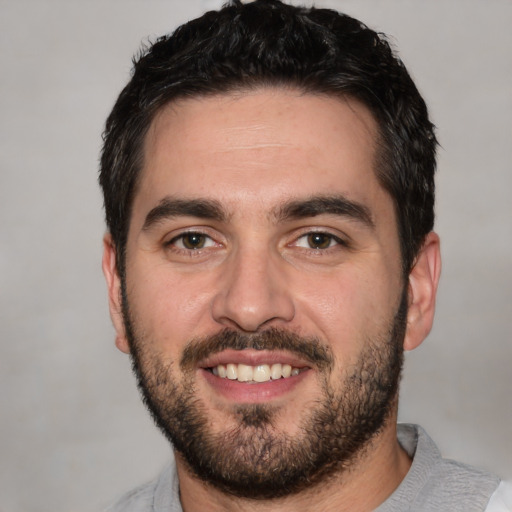 Joyful white young-adult male with short  black hair and brown eyes