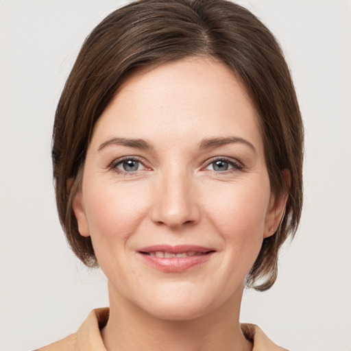 Joyful white young-adult female with medium  brown hair and grey eyes