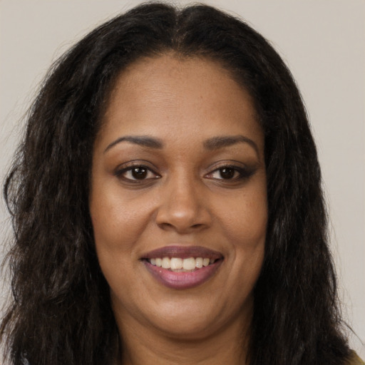 Joyful black young-adult female with long  brown hair and brown eyes