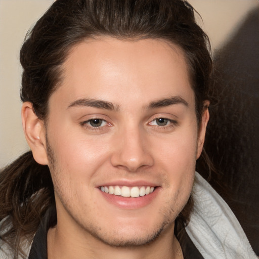 Joyful white young-adult male with long  brown hair and brown eyes