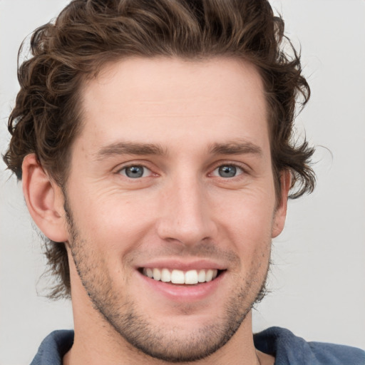 Joyful white young-adult male with short  brown hair and blue eyes