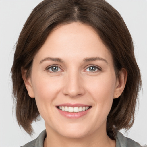 Joyful white young-adult female with medium  brown hair and grey eyes