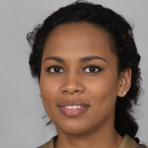 Joyful black young-adult female with long  black hair and brown eyes