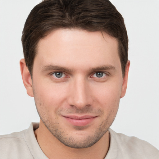 Joyful white young-adult male with short  brown hair and grey eyes