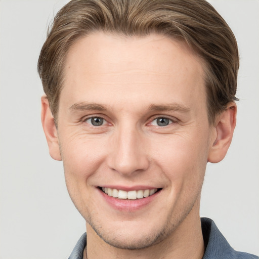 Joyful white young-adult male with short  brown hair and grey eyes