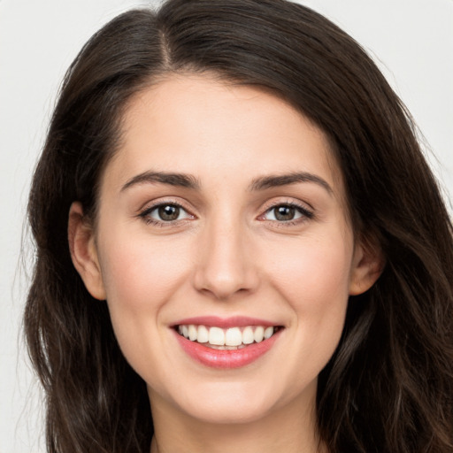 Joyful white young-adult female with long  brown hair and brown eyes