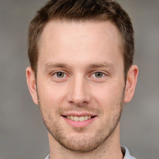 Joyful white young-adult male with short  brown hair and grey eyes