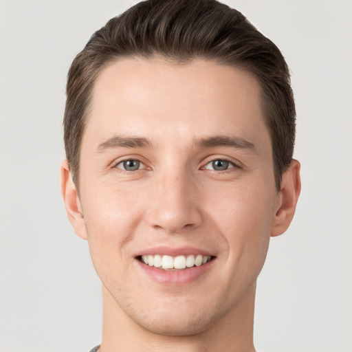 Joyful white young-adult male with short  brown hair and grey eyes