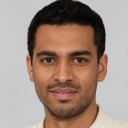 Joyful latino young-adult male with short  black hair and brown eyes