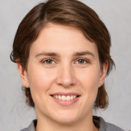 Joyful white young-adult female with medium  brown hair and grey eyes