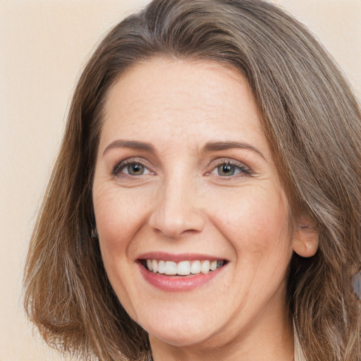 Joyful white adult female with long  brown hair and grey eyes