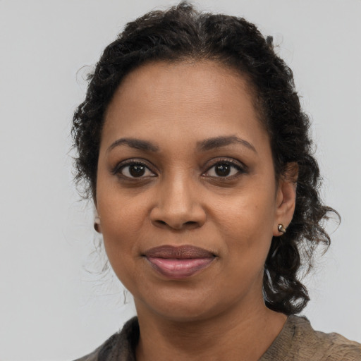 Joyful black young-adult female with long  brown hair and brown eyes